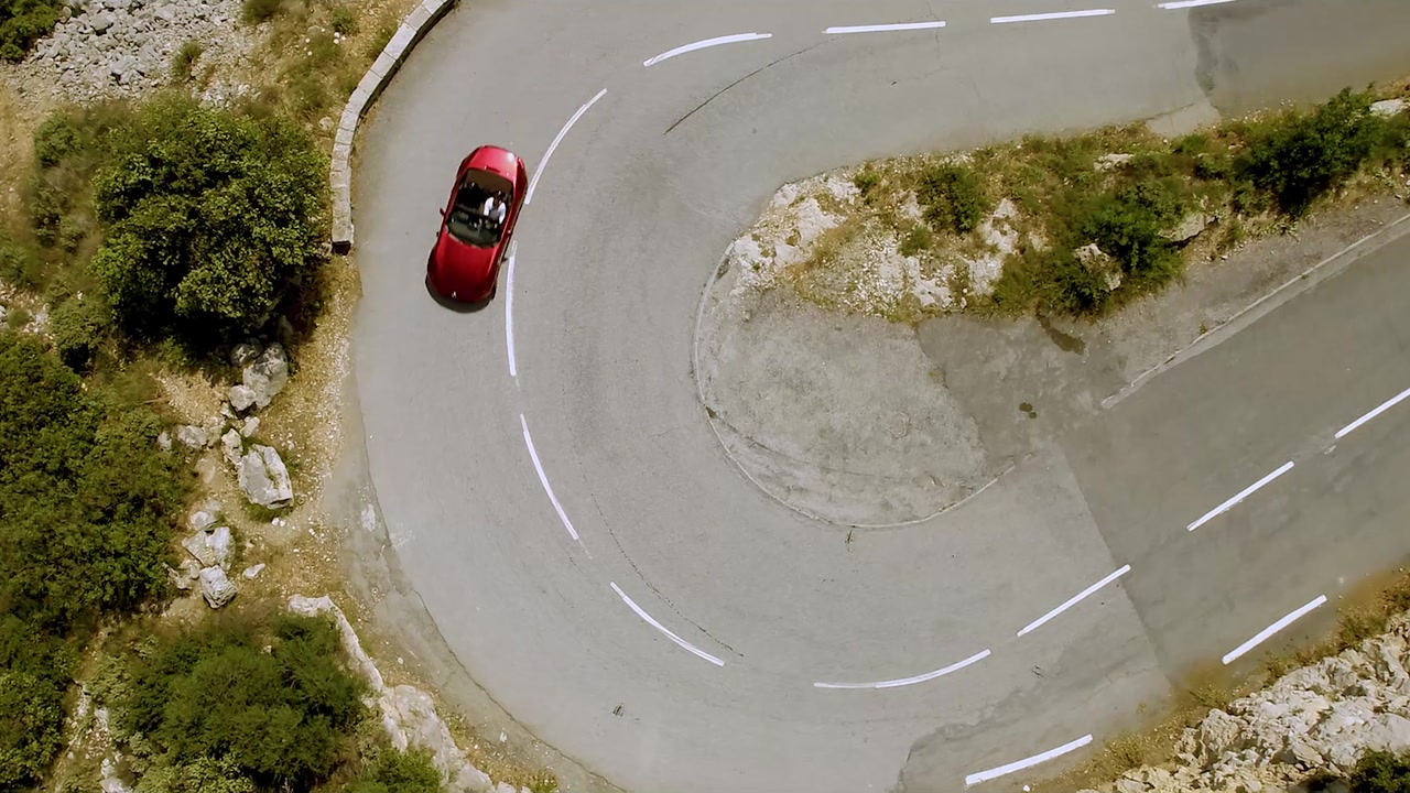 Red Mazda MX-5 on a hairpin turn, from above